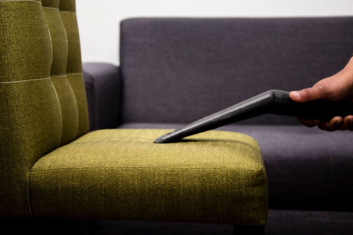 Cleaner vacuuming a fabric armchair